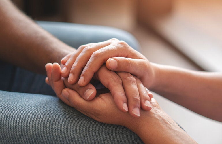 One person is offering support to another by holding his hands