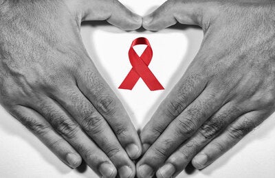 Hands forming a heart with AIDS ribbon over heart